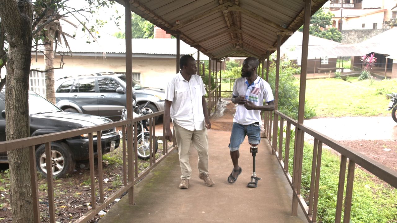 سامایی (سمت چپ) با ماکسول فورناه، بازیکن SLASA در مرکز ملی توانبخشی در سیرالئون ملاقات می کند.